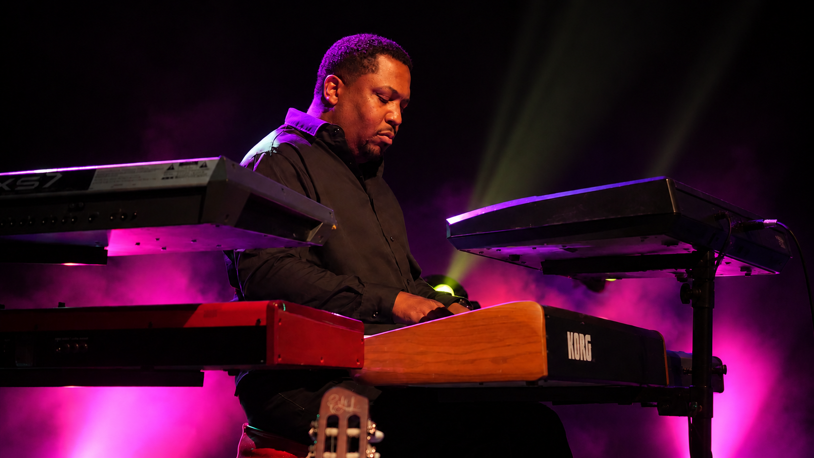 Vince Wiley performing at the keyboards under purple and blue stage lighting